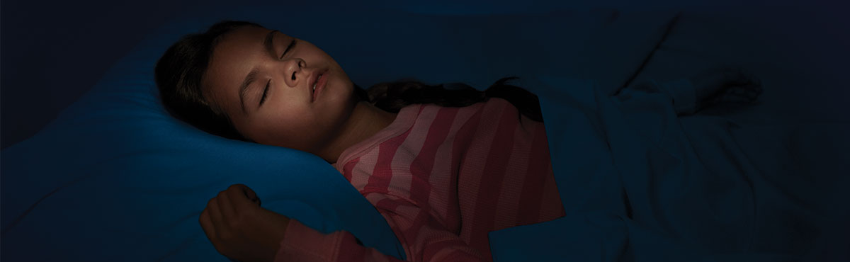 A child in a striped red shirt sleeping soundly in her bed